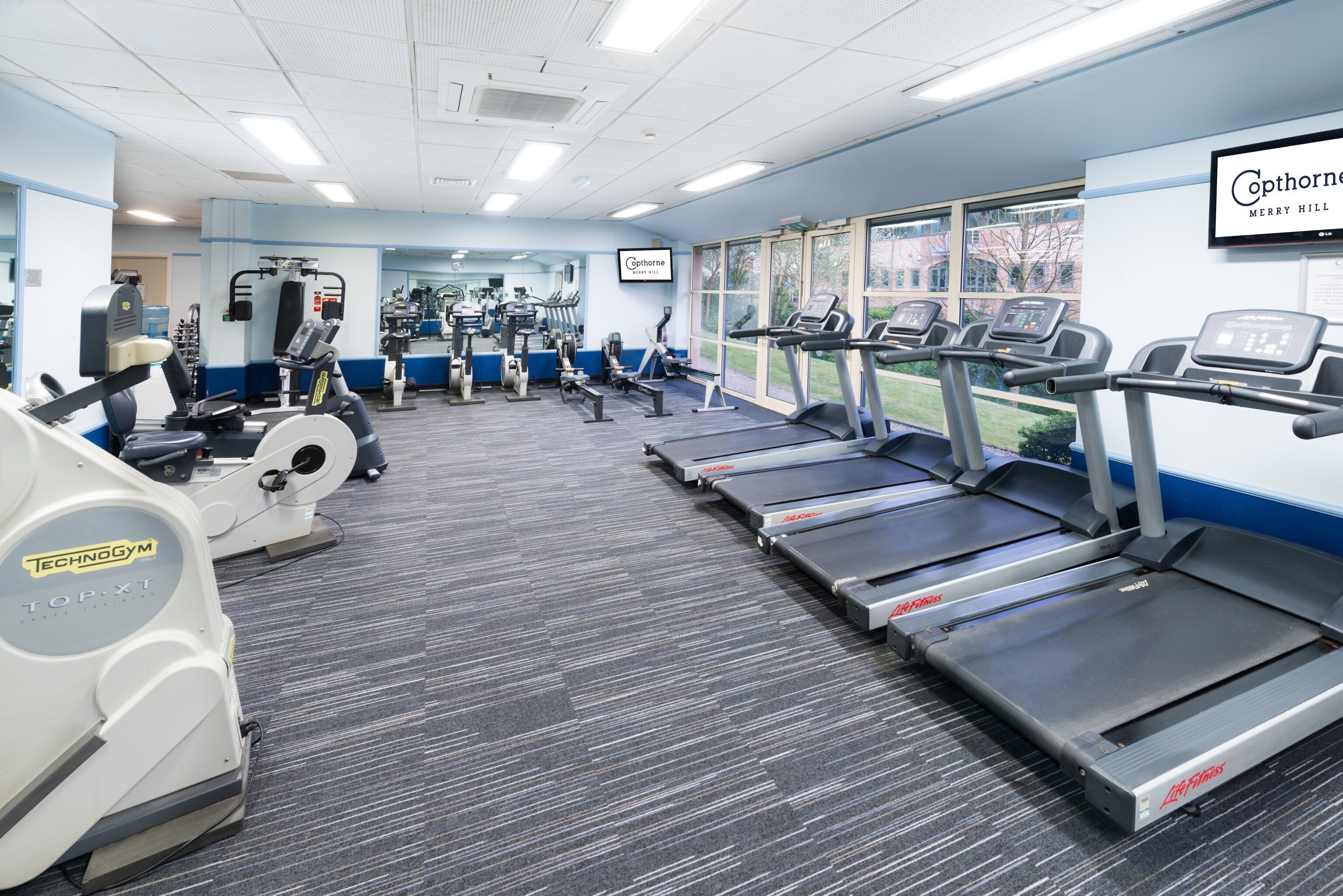 Un gimnasio con cintas de correr, bicicletas estáticas y máquinas de pesas.