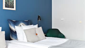 A bedroom with a bed, pillows, a desk lamp, and a chair.