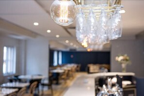 Un espace de salle à manger moderne avec une longue table et des chaises, un lustre orné de globes en verre transparent et un mur d’accent bleu.