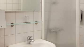 A bathroom with a white sink, a glass shelf, and a mirror.