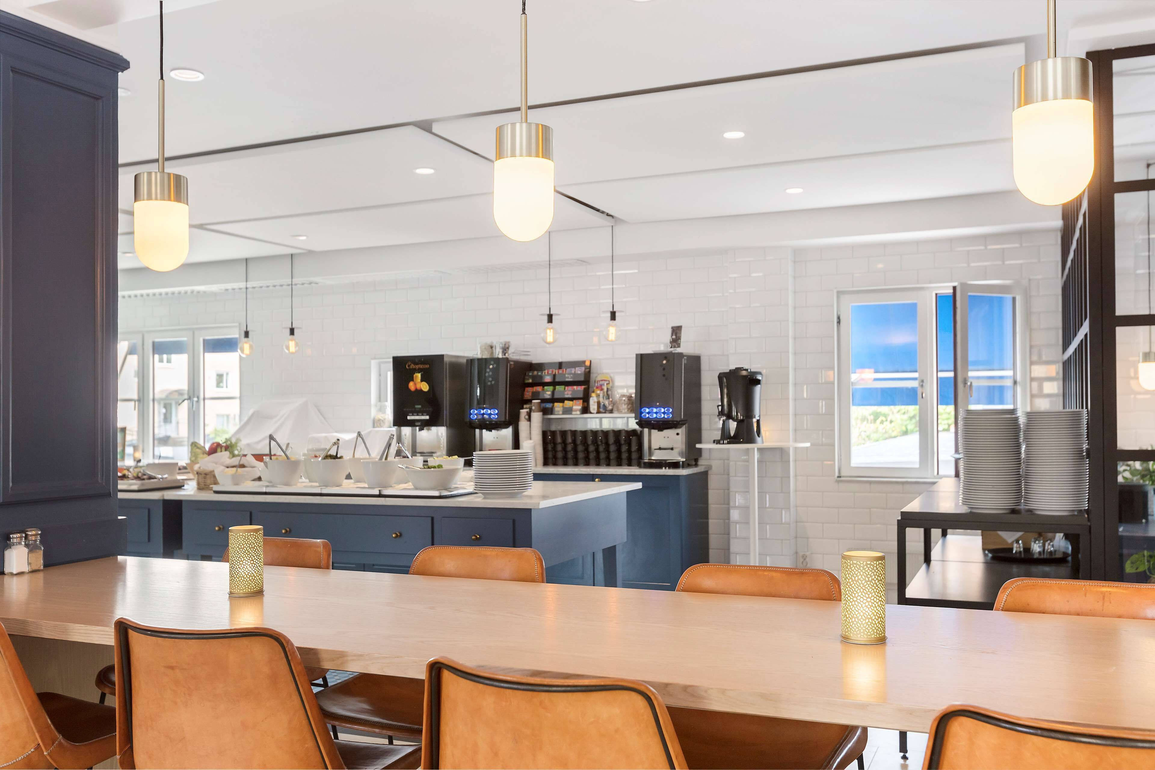 Una cocina moderna con una isla grande, electrodomésticos integrados e iluminación colgante.