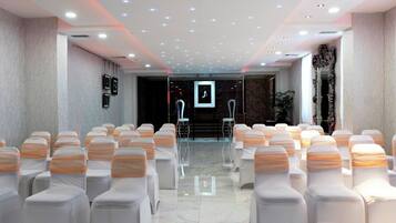 A conference room with rows of chairs and a stage.
