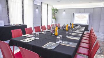 A conference room with a long table, red chairs, and a projector screen displaying "The Earl of Doncaster Hotel Restaurant Bar".