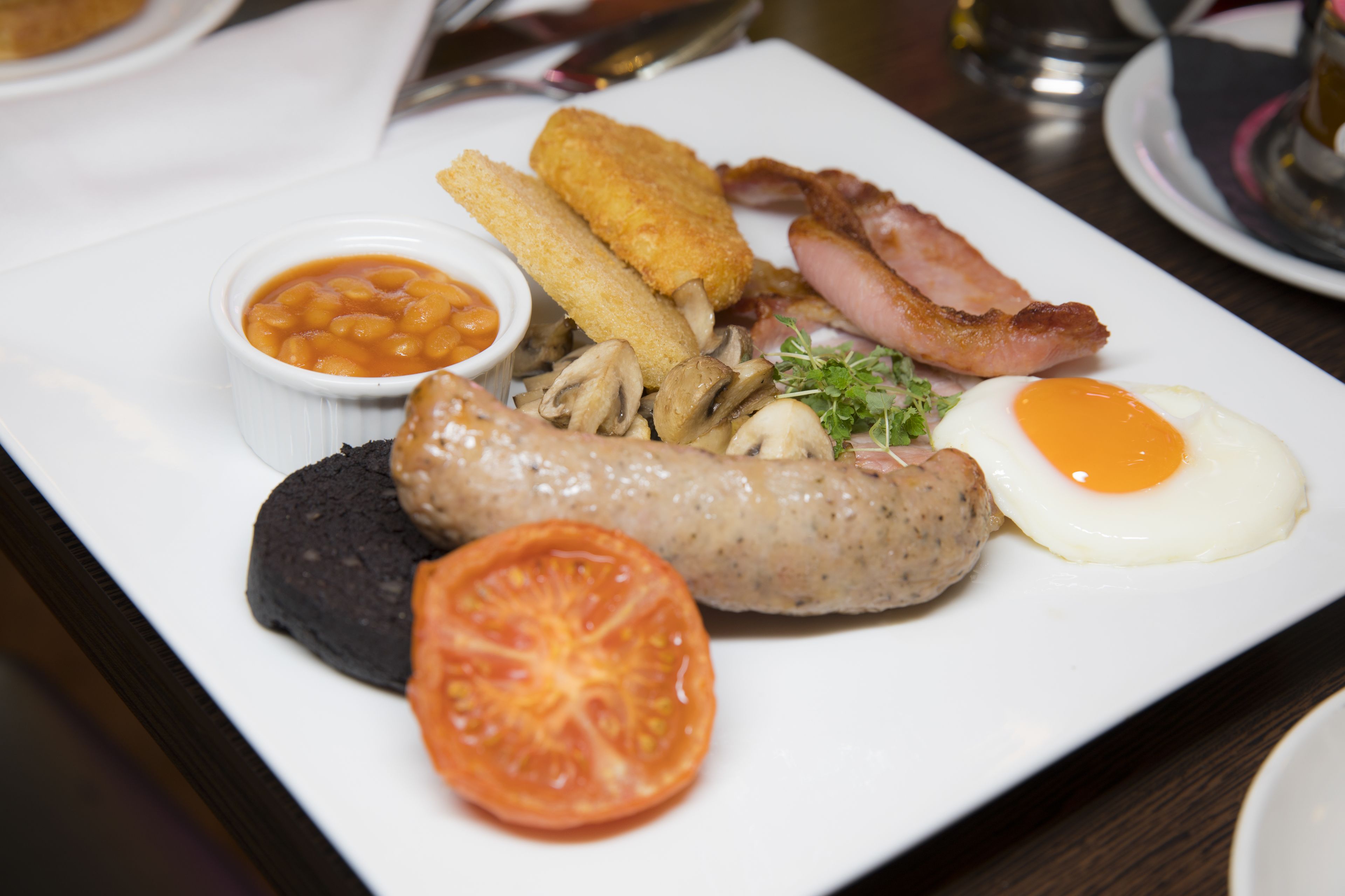 Un plato de comida para el desayuno con huevos, tocino, salchichas, champiñones y frijoles.