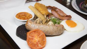 Un plato de comida para el desayuno con huevos, tocino, salchichas, champiñones y frijoles.