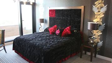 A bedroom with a large bed, a nightstand, a lamp, and a decorative wall piece.