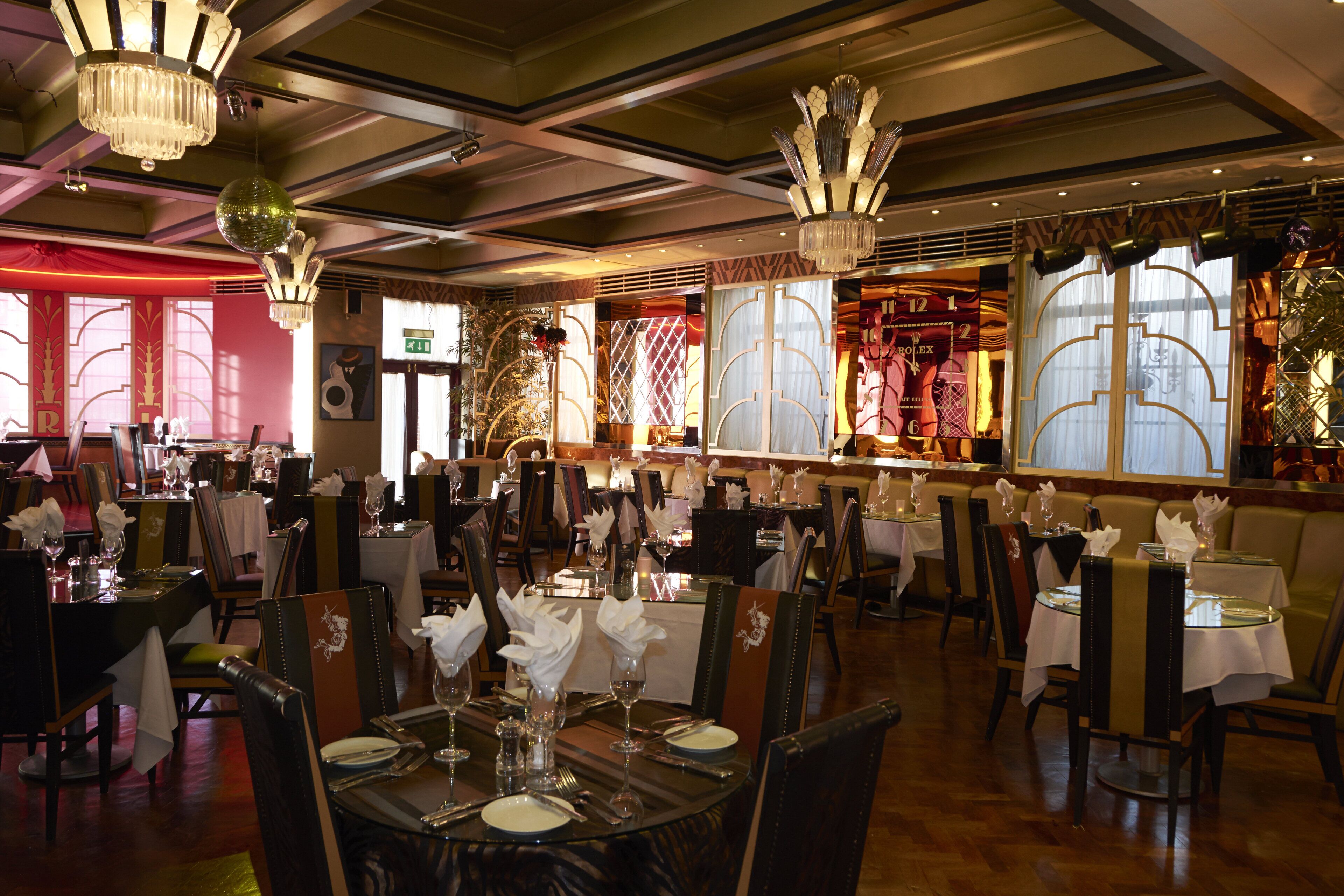 Un restaurante con varias mesas dispuestas para comer, con candelabros y elementos decorativos.