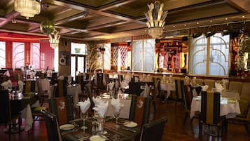 Un restaurante con varias mesas dispuestas para comer, con candelabros y elementos decorativos.
