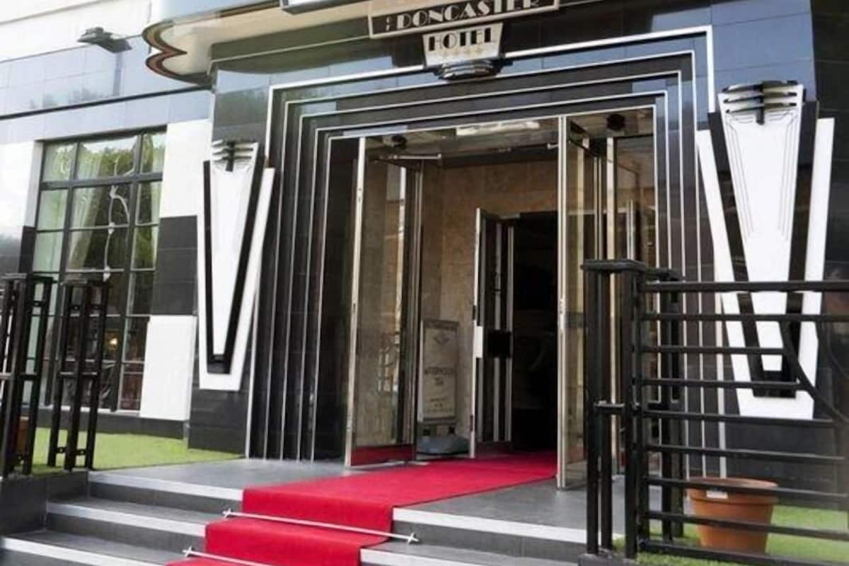 Een hotelingang met een rode loper, trappen en een vlag.
