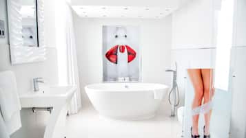 Un bagno moderno con una vasca da bagno indipendente, un lavandino e uno specchio grande.