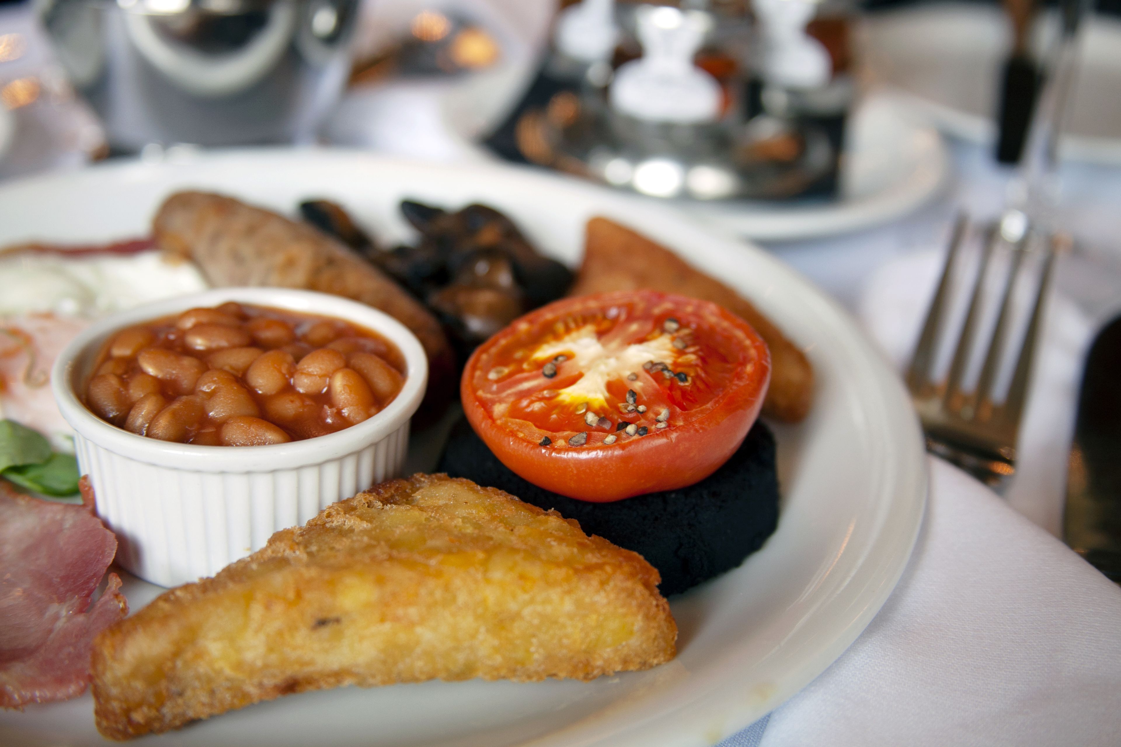 Un plato de comida con frijoles, un tomate y un trozo de comida frita.
