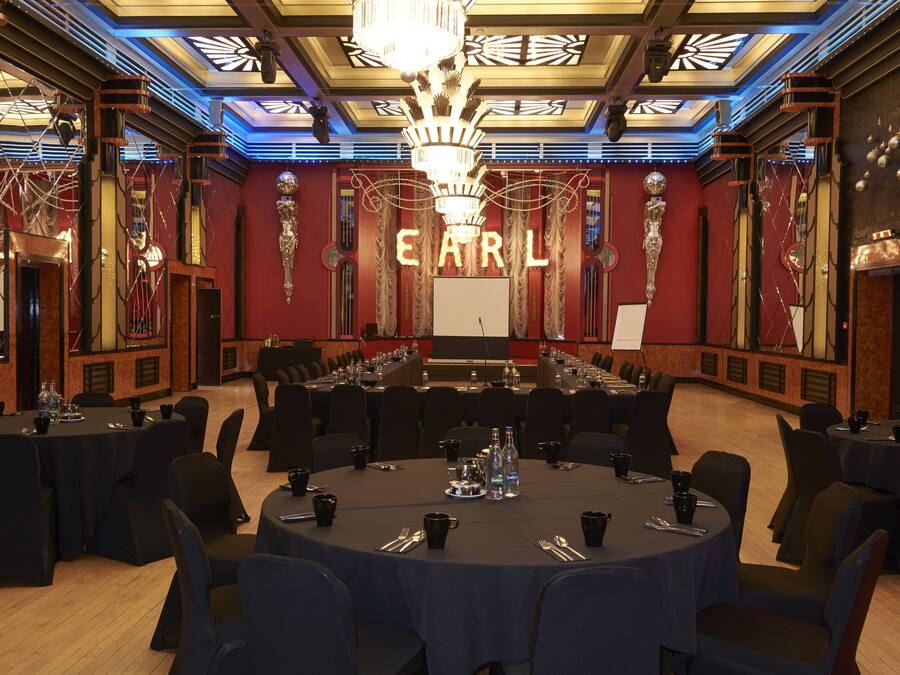 A conference room with round tables, chairs, and a large chandelier.