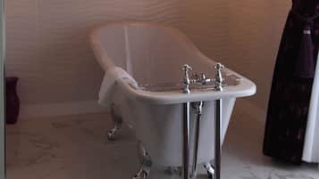 A bathroom with a freestanding bathtub, a vanity with a mirror, and a chandelier.