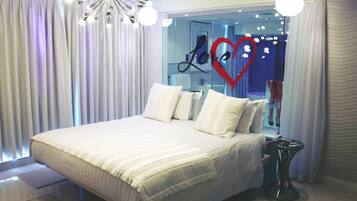 A modern bedroom with a large bed, white curtains, and a unique ceiling light fixture.