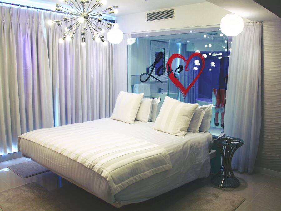 A modern bedroom with a large bed, white curtains, and a unique ceiling light fixture.