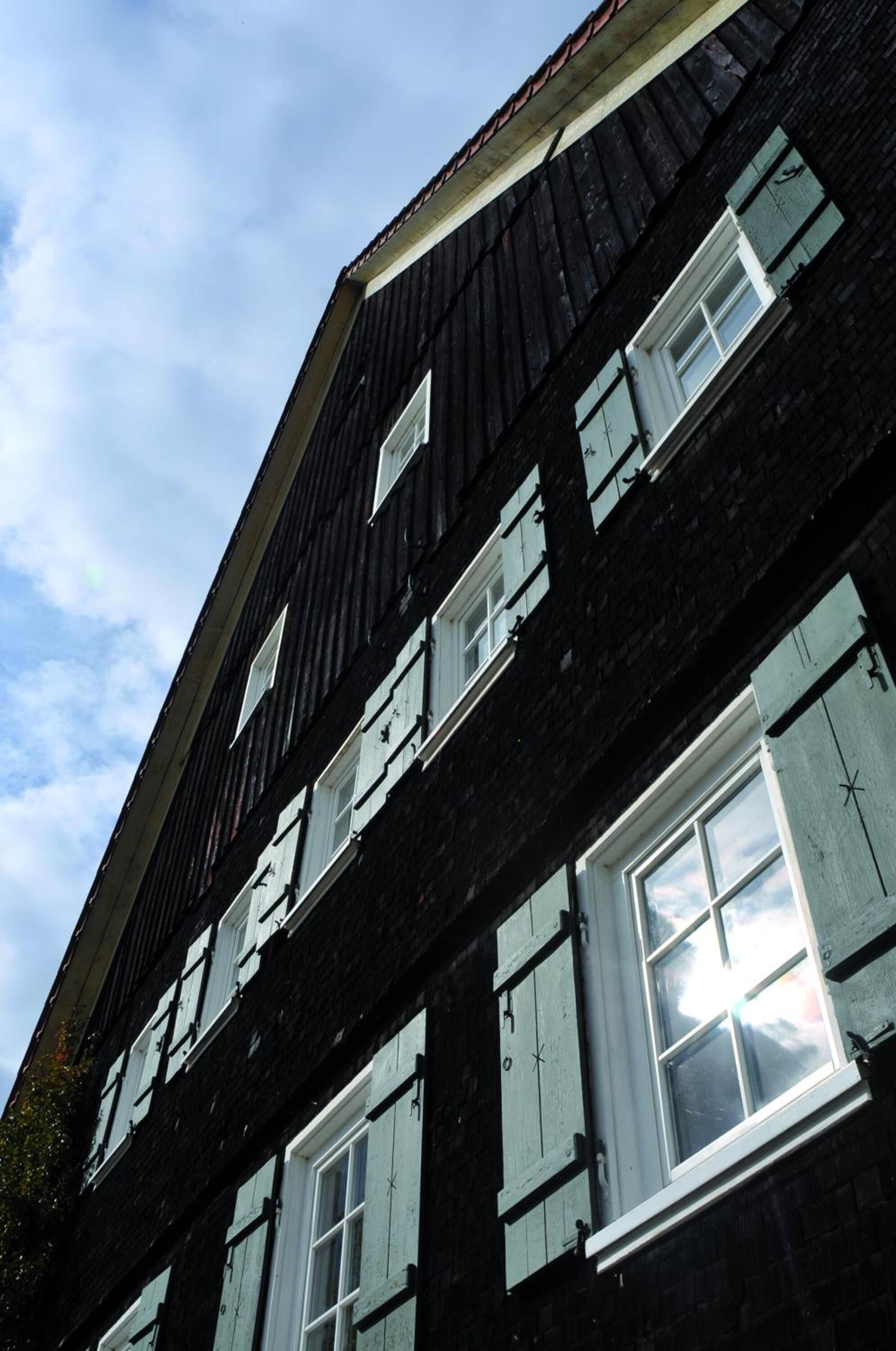 A multi-story building with a dark facade and white-framed windows.
