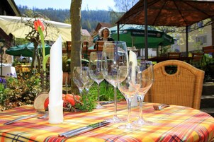 Una mesa dispuesta con copas de vino, cubiertos, un servilleta blanca y una flor de tulipán roja.