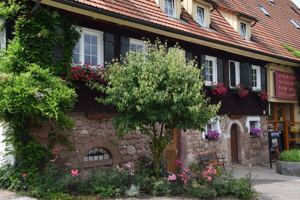 Situated in a charming stone building, this property features a traditional European architectural style with a steeply pitched roof and timber framing.