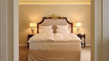 A bedroom with a large bed, two bedside tables with lamps, and a decorative headboard.