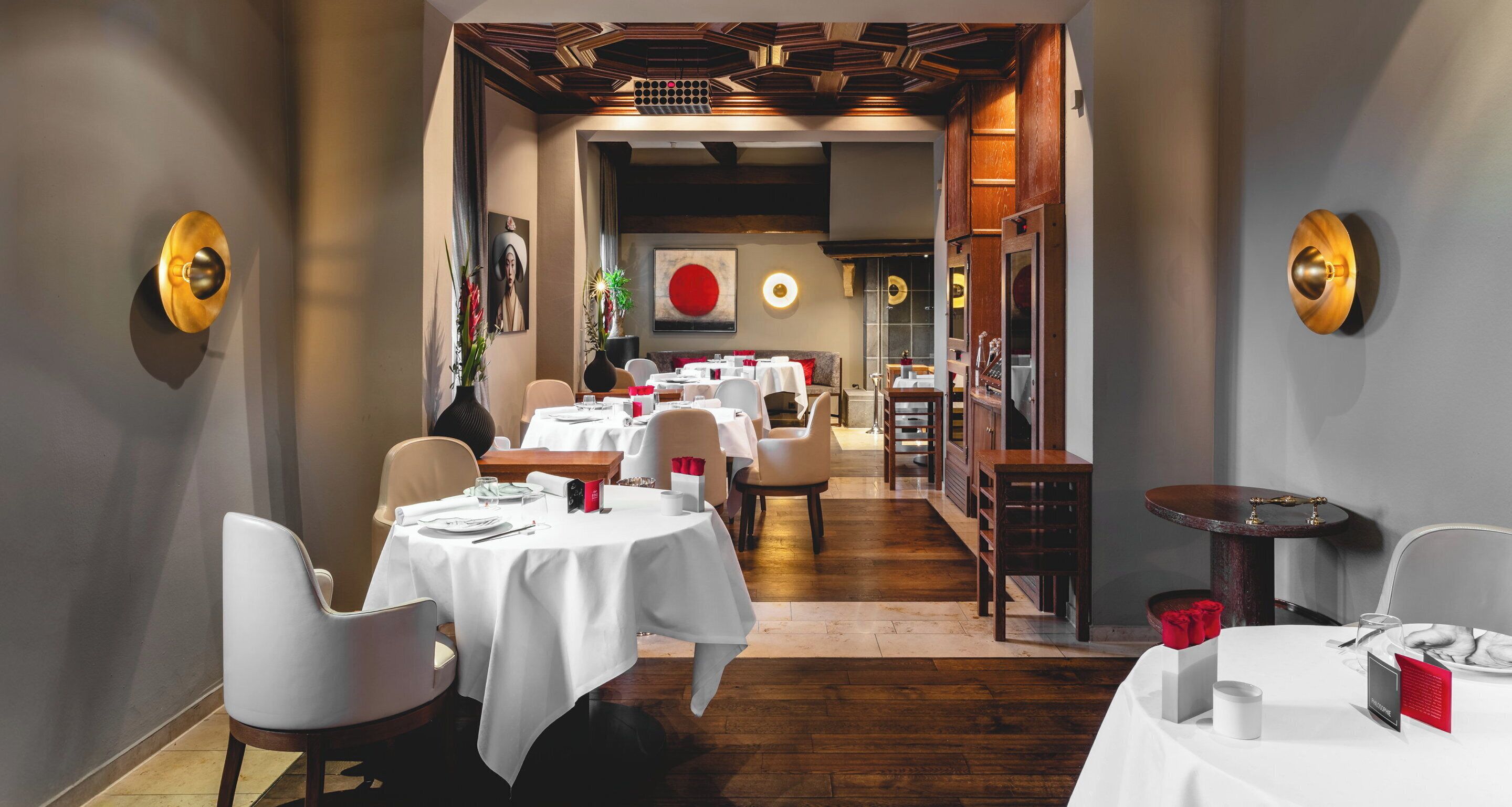 Un restaurante con manteles blancos, suelo de madera y decoración moderna.