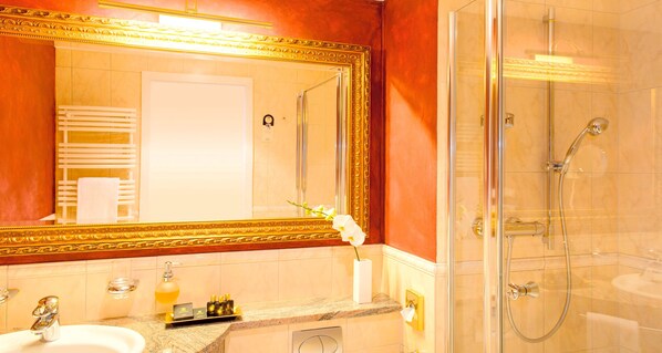 A bathroom with a large mirror, a sink, a shower, and a towel rack.