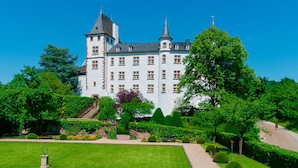 Un edificio grande e histórico con múltiples torres y un jardín bien cuidado.
