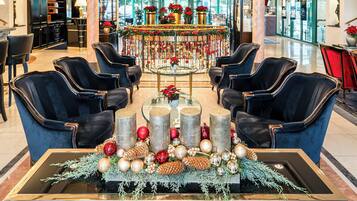 A lobby with a central round table, four blue armchairs, and a coffee table with a Christmas decoration arrangement.