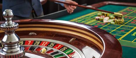 Una roulette con una pallina in movimento, una mano del banco e un tavolo verde con gettoni.