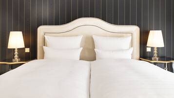 A double bed with a white headboard and two white pillows, flanked by two bedside tables with lamps.
