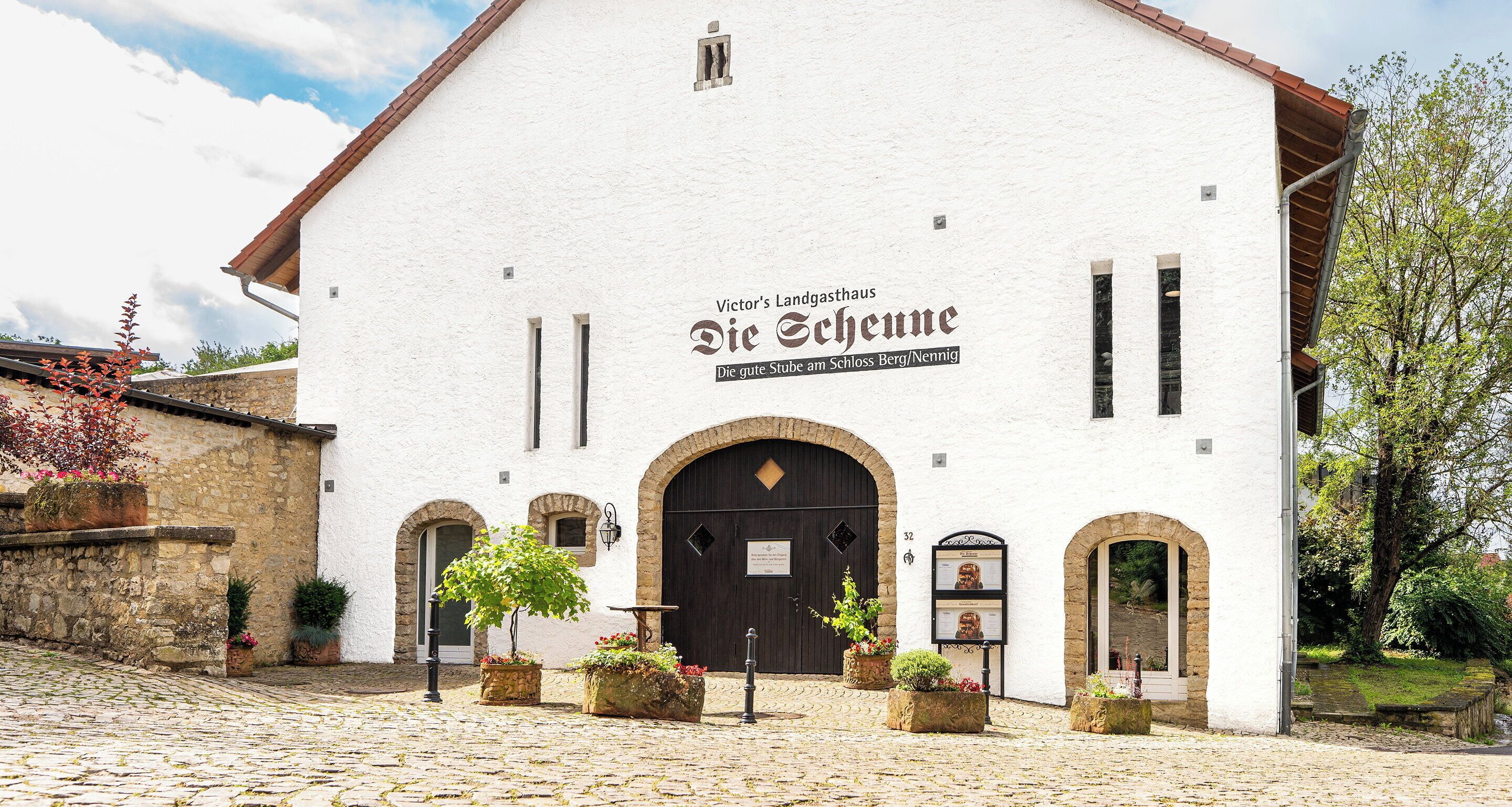 A white building with arched windows and a sign reading "Victor's Landgasthaus Die Schehne."