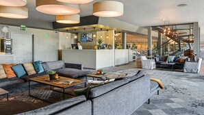Eine moderne Lobby mit einer Couch, einem Couchtisch und hängenden Pendelleuchten.