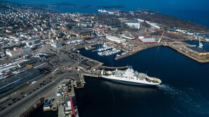 Eine Luftaufnahme einer Küstenstadt mit einem großen Schiff im Hafen, umgeben von Wohn- und Geschäftsgebäuden.