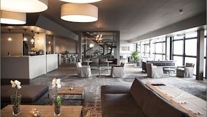 Eine großzügige Lobby mit einer Rezeption, Sitzbereichen und einer Treppe.