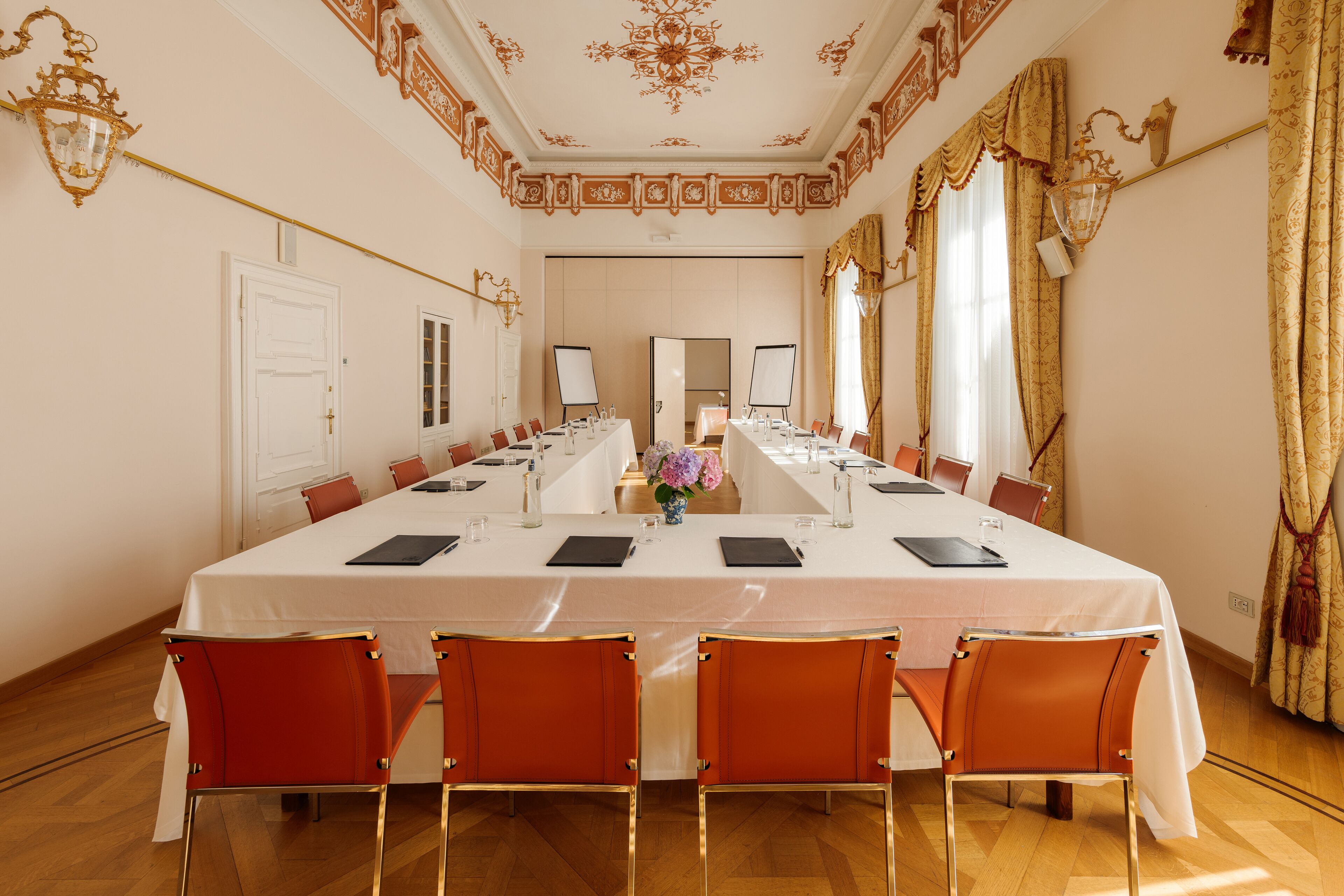 A conference room with a long table, chairs, and a white tablecloth.