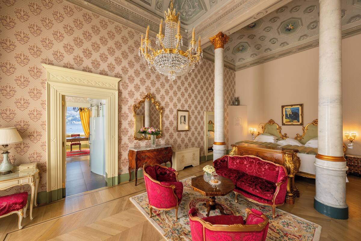 Une chambre luxueuse, ornée d’un imposant lustre, de meubles richement décorés et d’un grand lit agrémenté de détails dorés.
