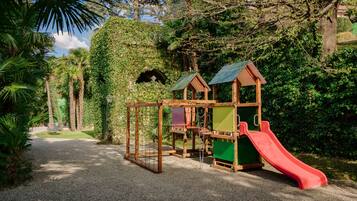Children can play and explore in this natural play area surrounded by lush greenery and trees.
