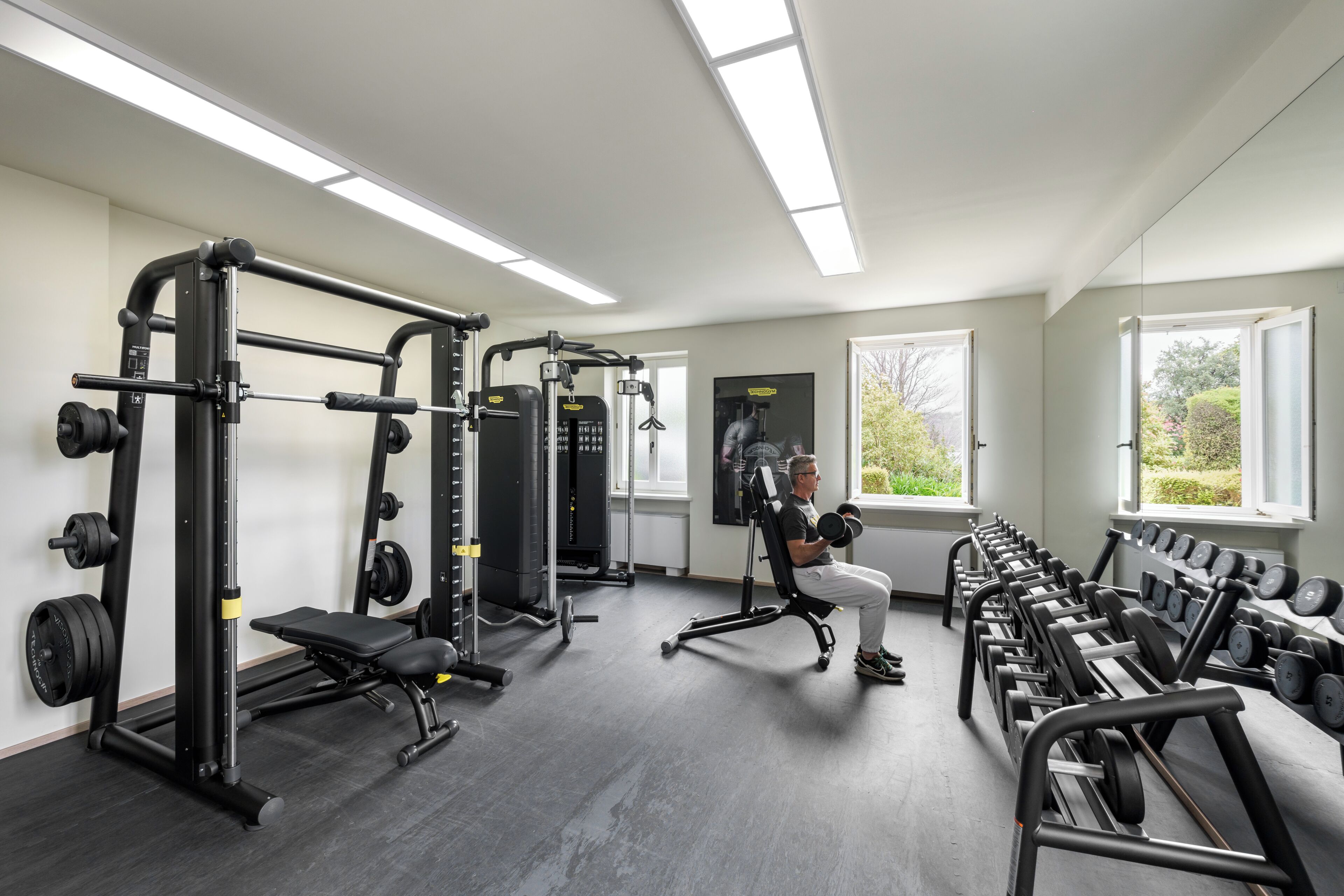 A gym with weightlifting equipment, benches, and dumbbells.
