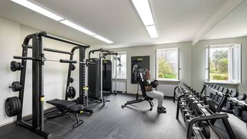 Een sportschool met gewichthefapparatuur, banken en gewichten.