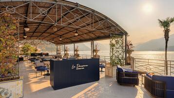 Un espace extérieur aménagé avec une structure couverte, un comptoir de bar et une vue sur l’eau.