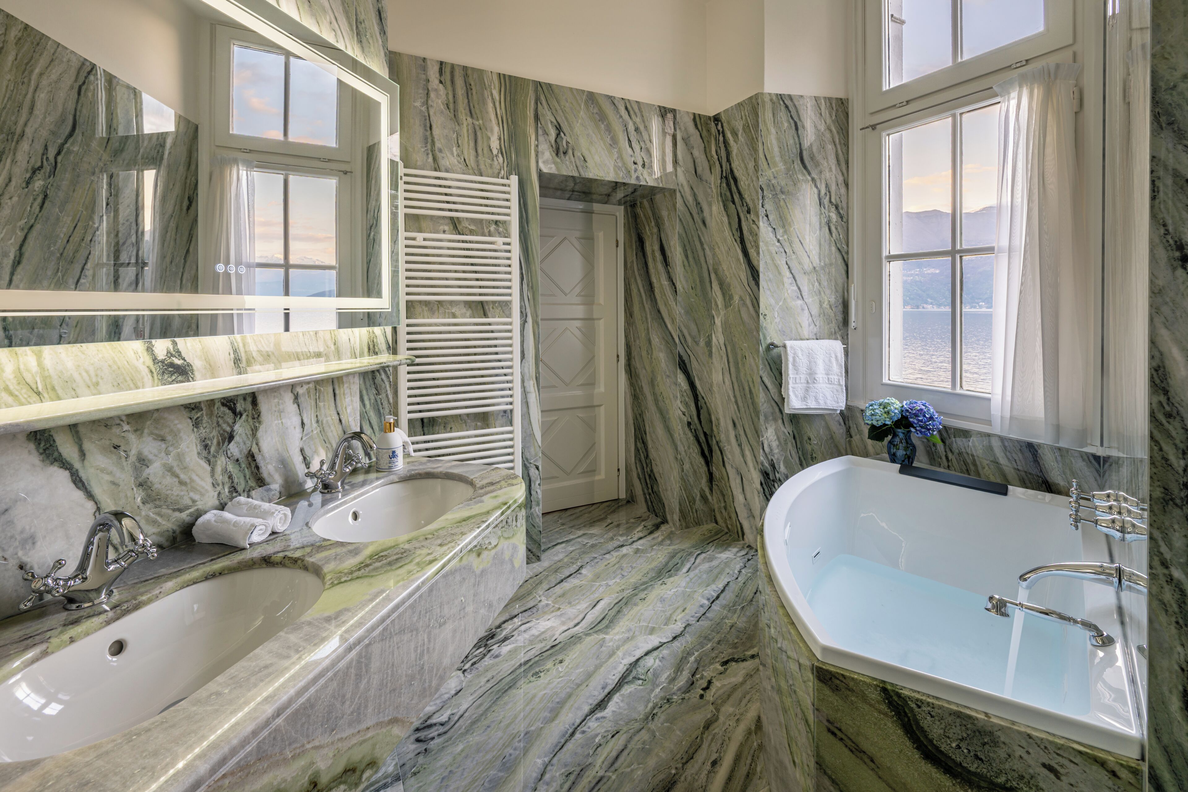 Une salle de bain avec deux lavabos, une baignoire et un grand miroir.