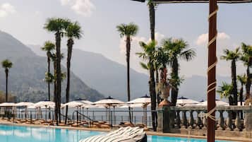 Una piscina techada, una piscina al aire libre, sombrillas