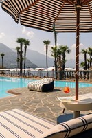Una piscina techada, una piscina al aire libre, sombrillas