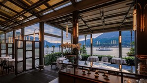Een restaurant met grote ramen, een bar en uitzicht op een waterpartij en bergen.