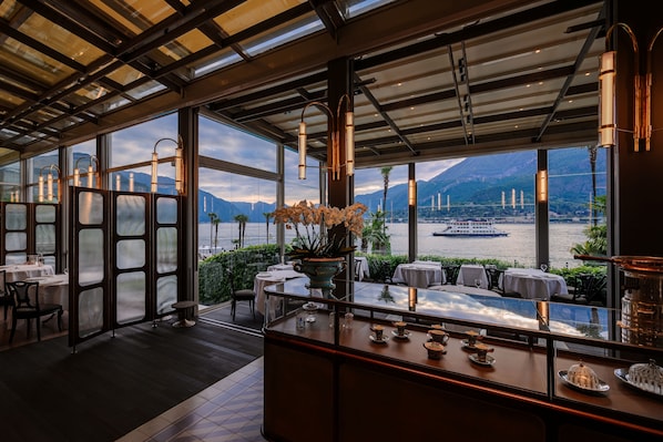A restaurant with large windows, a bar area, and a view of a body of water and mountains.