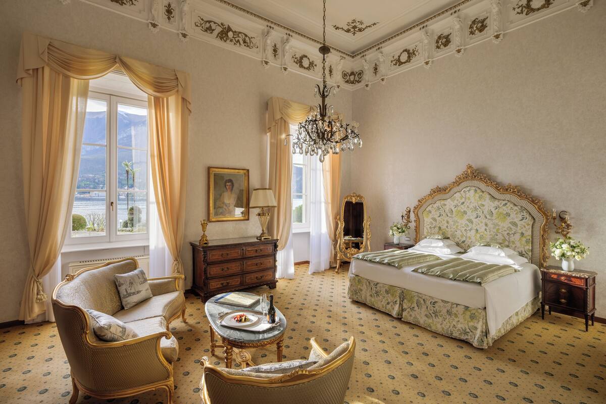 Une pièce comprenant un lit, une chaise, une table, une commode et un lustre.