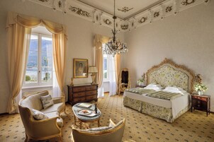 Una stanza con un letto, una sedia, un tavolo, una cassettiera e un lampadario.