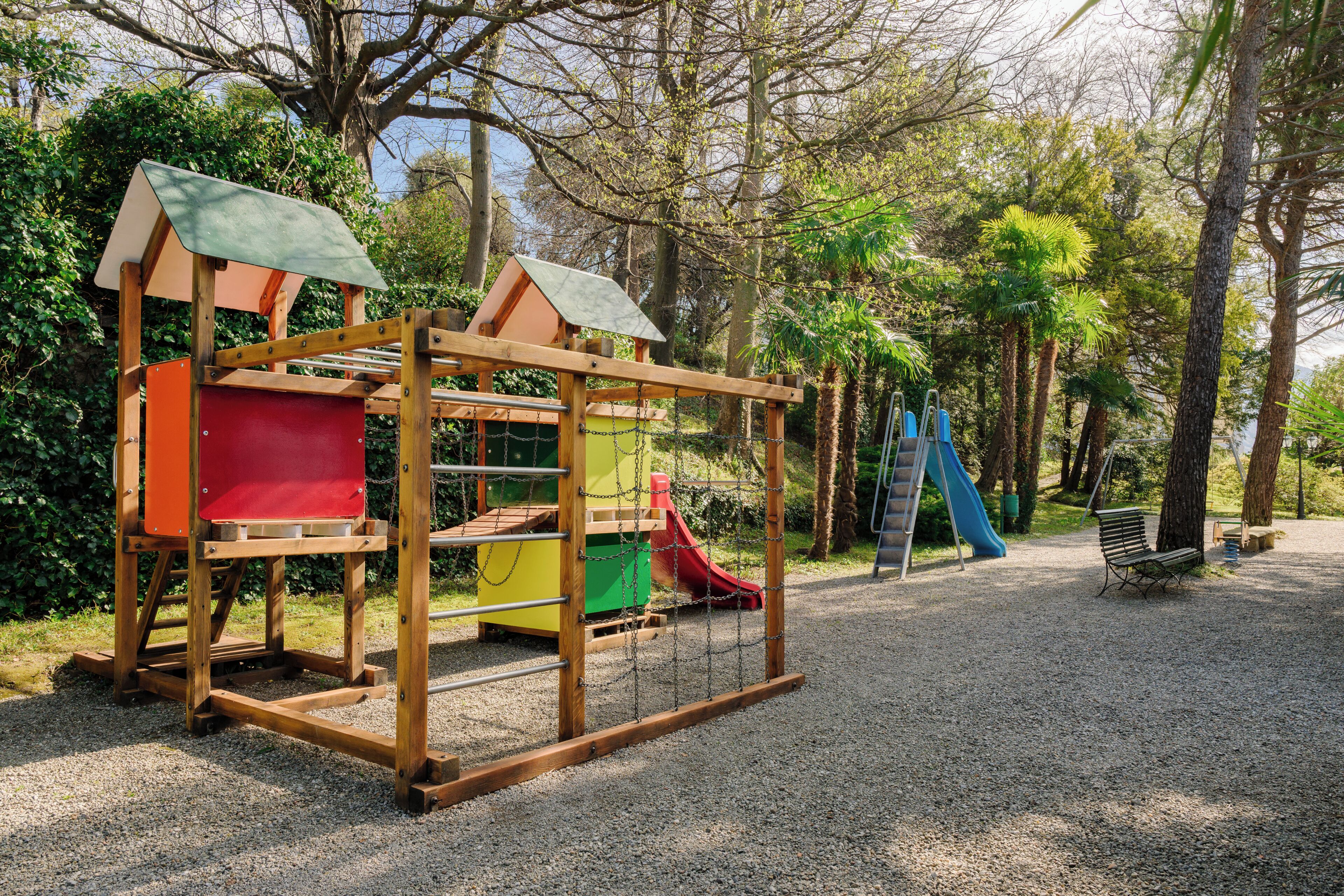Un parque infantil con tobogán, zona de escalada y banco.
