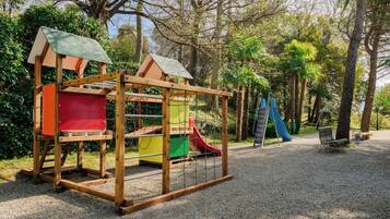 Un parque infantil con tobogán, zona de escalada y banco.