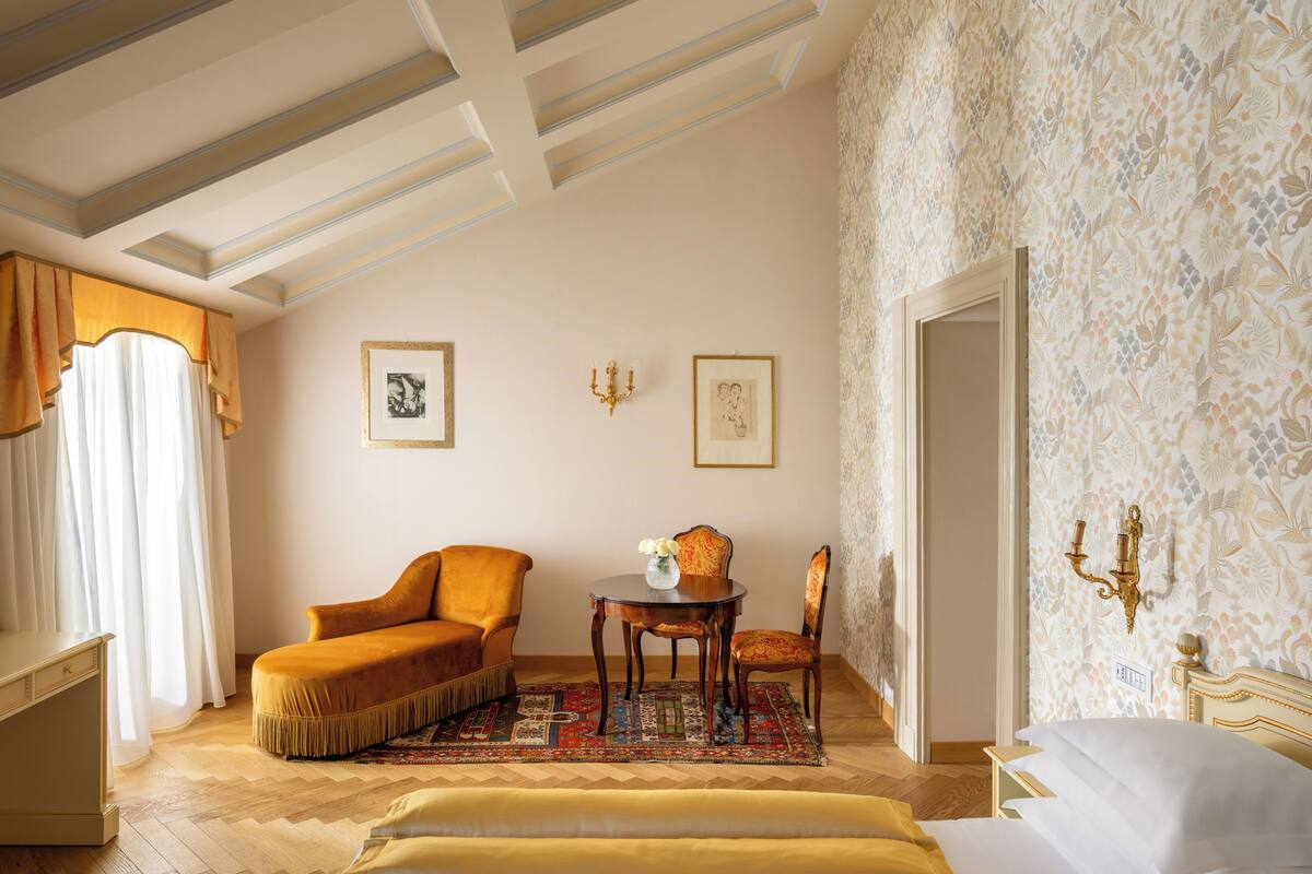 Une pièce comprenant un canapé, une petite table avec un vase, un mur à motifs et un lustre.