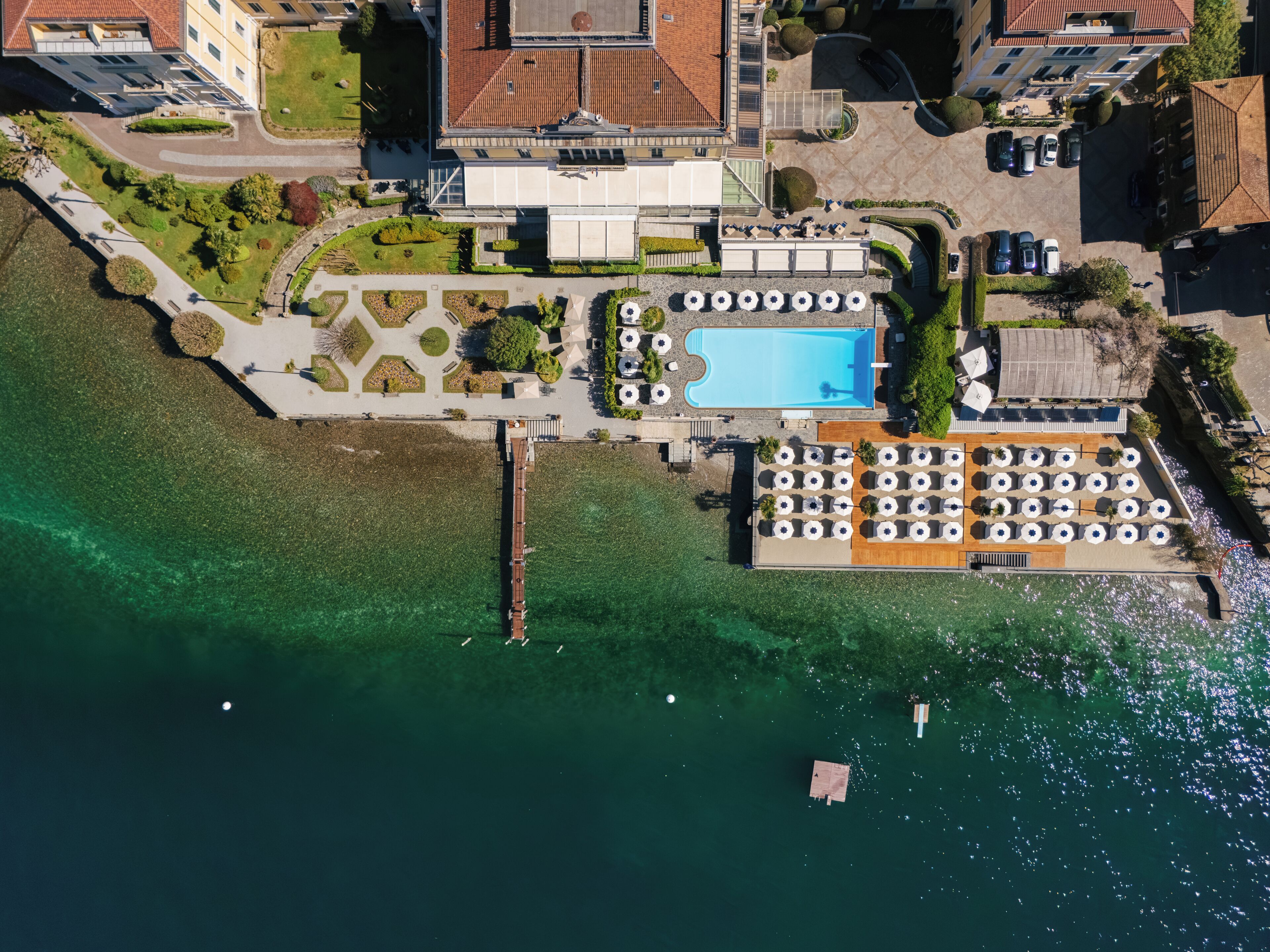 Una vista aerea di un hotel con piscina, area salotto all'aperto e un molo.